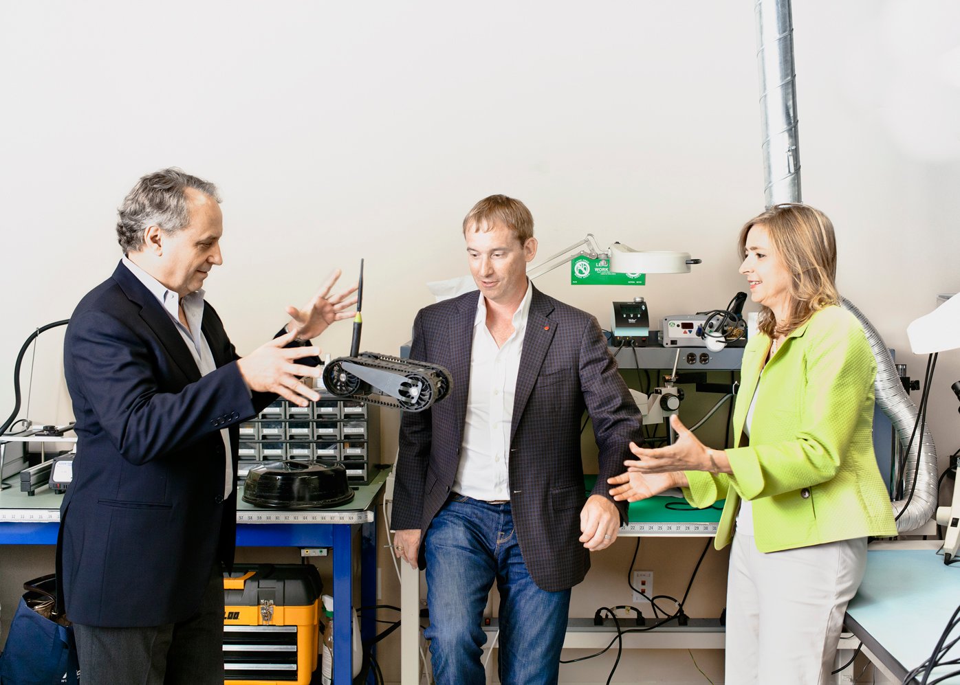 helen greiner on far right discussing a robot with two male colleagues on the left