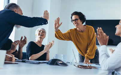 A group of professionals high-fiving around a table.