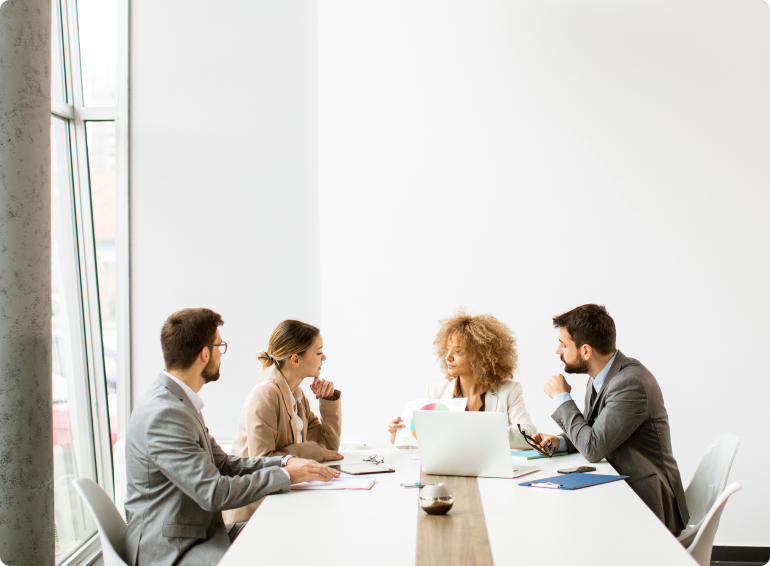 4 team members at a conference table talking