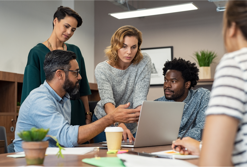 group of diverse business professionals working and surrounding a laptop