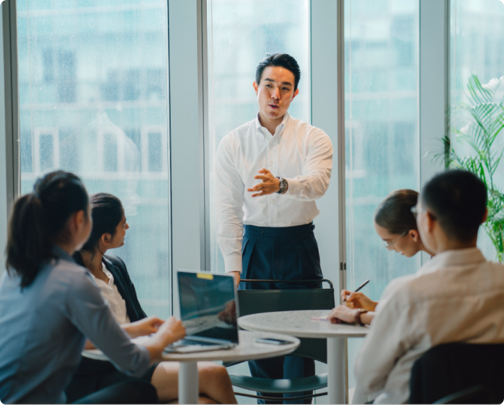 business man leading meeting while 4 colleagues take notes