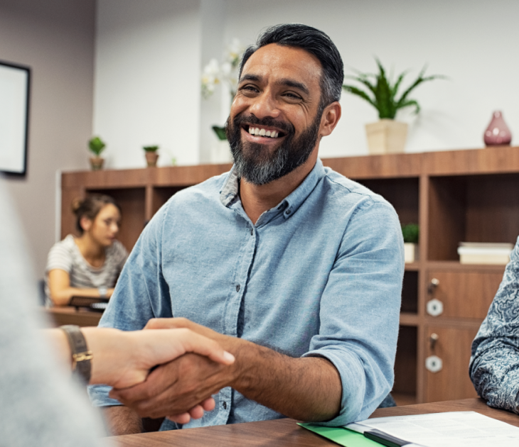 man with beard smiling and shaking hands with someone out of frame