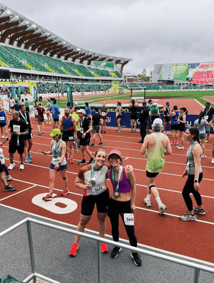 Hunt Club’s Customer Success Manager, Elyse Mathos, holding a medal and posing with a friend after a marathon race