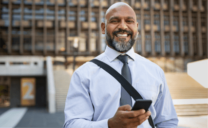 A professional smiling while working from their phone outside.